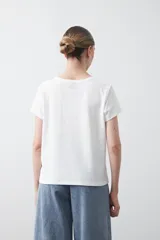 Remera básica de manga corta en color blanco, con cuello redondo y detalle de pliegues sutiles en los hombros.