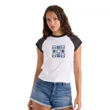 Remera Volcom de manga corta tipo raglán, modelo Kick It Game Day Crop Tee. Color blanco en el cuerpo con mangas y cuello en negro. Presenta un estampado frontal centrado con un diseño gráfico en tonos azules y negros.