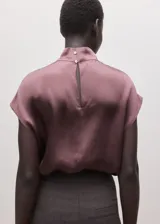 Blusa de seda con cuello alto y diseño sin mangas, de corte recto y acabado satinado.