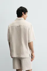 Camisa negra de manga corta, confeccionada en lino con corte relaxed fit, cuello bowling y cierre frontal de botonadura.