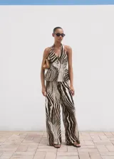Pantalón wide leg de tiro medio con estampado de cebra, confeccionado en mezcla de lino y algodón. Cuenta con bolsillos laterales, trabillas para cinturón y cierre frontal oculto con botón, gancho y cremallera.