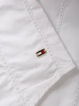 Blusa blanca de algodón orgánico con cuello en V, mangas largas abullonadas con puños abotonados y detalles de encaje vertical.