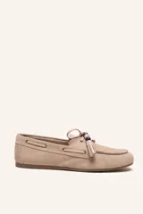 Mocasín de gamuza color beige, con cordones laterales, detalle de borla en el empeine con cuentas decorativas y suela plana de goma.