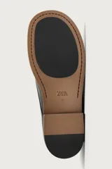 Zapato de vestir tipo derby de color negro, confeccionado en cuero con forro y plantilla de cuero, horma cuadrada y suela con ligero tacón.