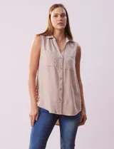 Camisa sin mangas color beige, marca Zac & Rachel, confeccionada en lino. Presenta escote en V, abertura frontal con botones, dos bolsillos delanteros y terminación con botones en los laterales.