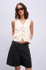 Chaleco de punto color crema con escote en V y cierre frontal con botones a tono.