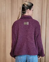 Chaqueta de textura bouclé en color bordó, con corte oversize, cuello camisero, cierre frontal y bolsillos laterales.