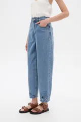 Pantalón jean slouchy de tiro alto, color natural, con detalle de bordadoado en el borde inferior.