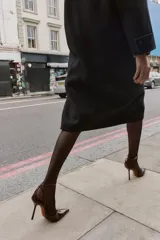 Zapato destalonado de tacón alto fino con acabado efecto acharolado. Presenta un diseño de punta fina y cierre mediante tira con hebilla ajustable al tobillo.