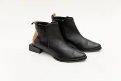 Botín corto de cuero negro con detalle de cuero dorado en el talón y textura de cocodrilo en el lateral. Tiene cierre lateral y taco cuadrado.