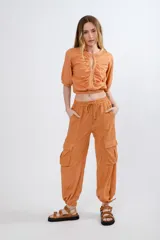 Pantalón cargo color naranja de lino, con cintura elastizada ajustable con cordón, bolsillos laterales con solapa y jareta en el ruedo.