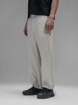 Pantalón cargo de corte oversize confeccionado en microfibra elastizada color beige. Presenta cintura elástica, bolsillos laterales y un bolsillo cargo con cierre de broche a presión. Incluye un sistema de elásticos con tancas en los tobillos para ajustar la apertura.