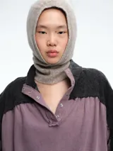 Campera de estilo casual con diseño bicolor, combinando paneles en color gris oscuro y malva. Presenta cuello alto con cierre frontal de botones a presión, mangas largas con puños elásticos y ruedo ajustable con cordón.