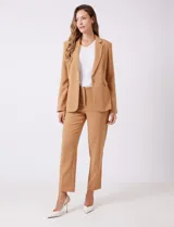 Blazer sastrero entallado color beige, con cuello de solapa, cierre frontal con un botón a tono y hombreras estructuradas. Presenta bolsillos laterales con solapa y forro interno.