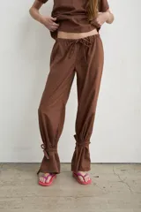 Pantalón recto marrón de lino y algodón, con tiras regulables en los tobillos para ajustar.