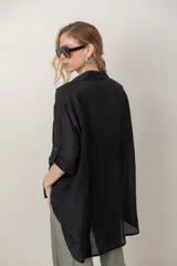 Camisa oversize de seda negra, con cuello camisero, cierre frontal con botones y mangas cortas con vuelta.