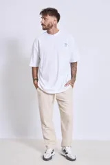 Remera de algodón color verde oliva, corte oversize, con cuello redondo y un pequeño logo bordado en el pecho.