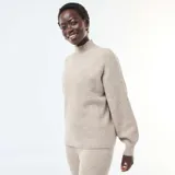 Sweater de punto canalé en color beige, con cuello alto y mangas largas con puños ajustados.