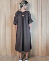 Vestido midi de corte holgado, con escote en V y cordones ajustables. Presenta mangas tres cuartos abullonadas con puños elásticos.