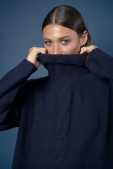 Buzo de cuello alto tejido en lana, con diseño de ochos en el centro y mangas largas con hombros caídos.