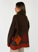 Sweater de cuello alto con diseño de rombos en tonos grises y detalles en rojo. Presenta puños y ruedo en tejido acanalado de color gris claro.