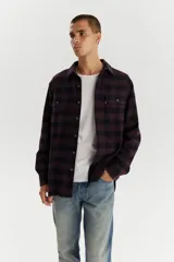 Camisa a cuadros color púrpura y negro, de corte recto, manga larga y dos bolsillos frontales con botón.