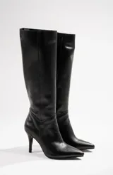 Botas de cuero negro, de caña alta, con punta fina y taco aguja.