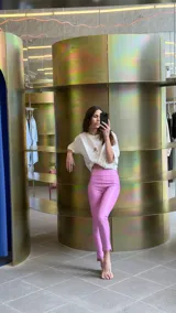 Pantalón largo de ecocuero color lila, con tiro alto, calce ajustado y botamanga irregular.