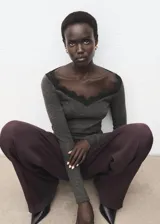 Remera de manga larga gris oscuro con cuello en V adornado con detalles de puntilla negra.