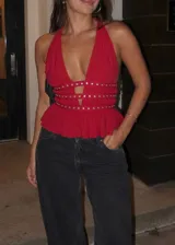 Top halter de microtul rojo con escote en V profundo, tiras fruncidas en la cintura con tachas metálicas y detalle de aberturas frontales. Presenta un diseño corto con vuelo en la parte inferior.