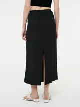 Falda maxi color marrón, con diseño pinzado en la cintura y un tajo delantero central que aporta movimiento.