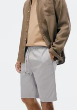 Bermuda de corte recto en color negro, confeccionada en tejido de algodón, con cierre frontal y bolsillos laterales.