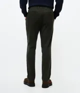 Pantalón slim de sarga lavada color marrón, con cierre de botón y cremallera, trabillas para cinturón y bolsillos laterales y traseros.