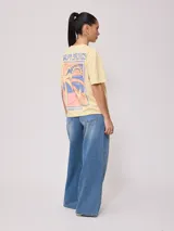 Remera color salmón de corte holgado, con estampado pequeño en el frente que incluye un arcoíris y el texto "Rusty Club".