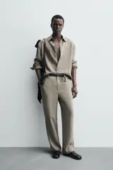 Camisa de manga larga color verde oliva, confeccionada en lino lavado con efecto ligeramente arrugado. Presenta cuello italiano y cierre frontal de botones.