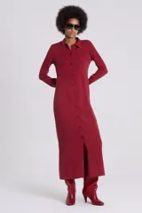 Vestido camisero largo color rojo oscuro, de manga larga y cuello camisero. Presenta un cierre frontal completo con botones oscuros y una abertura en el ruedo.