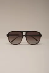 Anteojos de sol estilo aviador con montura superior negra y parte inferior carey (marrón jaspeado). Los lentes son degradados en tonos marrones.