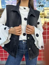 Blusa al cuerpo color blanco con estampado de lunares negros, cuello redondo y mangas largas con terminación acampanada.