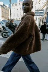 Chaqueta de cuello solapa y manga larga, con diseño de doble faz que combina tejido efecto ante y borreguillo. Cuenta con cierre frontal de botones y bolsillos delanteros.