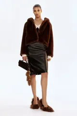 Pollera tubo de tiro alto confeccionada en tejido revestido con acabado efecto cuero. Presenta diseño de largo hasta la rodilla, bolsillos delanteros con cierre metálico y costuras verticales decorativas.