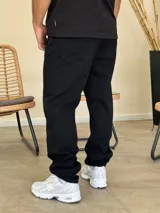 Pantalón jean de corte recto y holgado, color negro, con diseño de cinco bolsillos y cierre frontal con botón y cremallera.