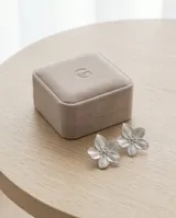 Caravanas de acero con diseño de flor de cinco pétalos con textura estriada y centro con pequeños puntos en relieve.