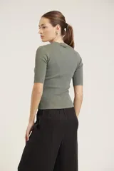 Blusa de punto acanalado color negro, con cuello alto y mangas cortas.