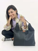 Cartera de cuero genuino negro, modelo Mora de Chabas, tipo shopper grande de diseño slouchy con costuras visibles, asas de hombro y detalle de etiqueta de cuero marrón en el frente. Incluye un sobre interno removible sin forro.