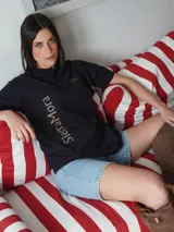 Polo shirt de manga corta color azul marino con cuello y tapeta de botones. Presenta un bordado dorado con las iniciales "SM" en el pecho derecho y un estampado vertical en el costado izquierdo con el texto "Terra Mora".