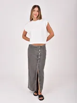 Falda larga de denim color gris oscuro, con diseño cruzado frontal (wrap) que se ajusta con botones plateados, creando una abertura pronunciada.