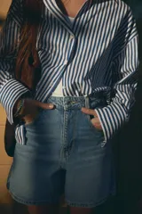 Shorts de jean tiro alto con diseño mom fit, cinco bolsillos y cierre frontal con cremallera y botón.