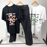 Remera negra de mangas cortas con estampa en la espalda con la frase "Boundless art" y una flor abstracta color salmón.