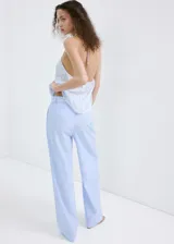 Pantalón de corte recto y tiro bajo, de diseño amplio y fluido, con patrón de rayas verticales finas.