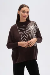 Sweater de tejido marrón oscuro con cuello alto y un gran aplique bordado en blanco con diseño abstracto que simula un abanico o flor.